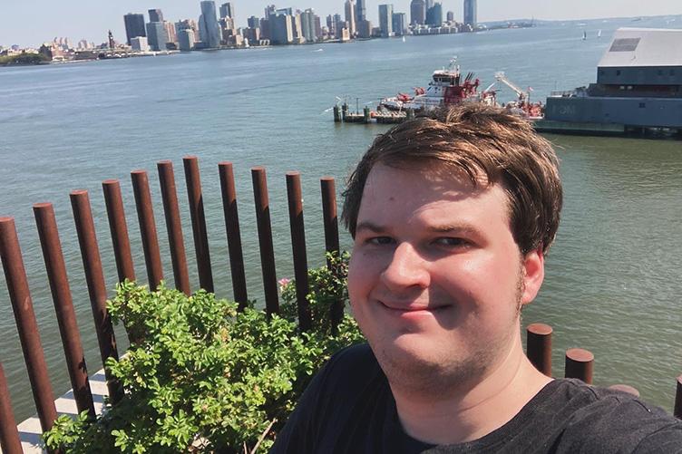 Man taking selfie in front of a city skyline and water